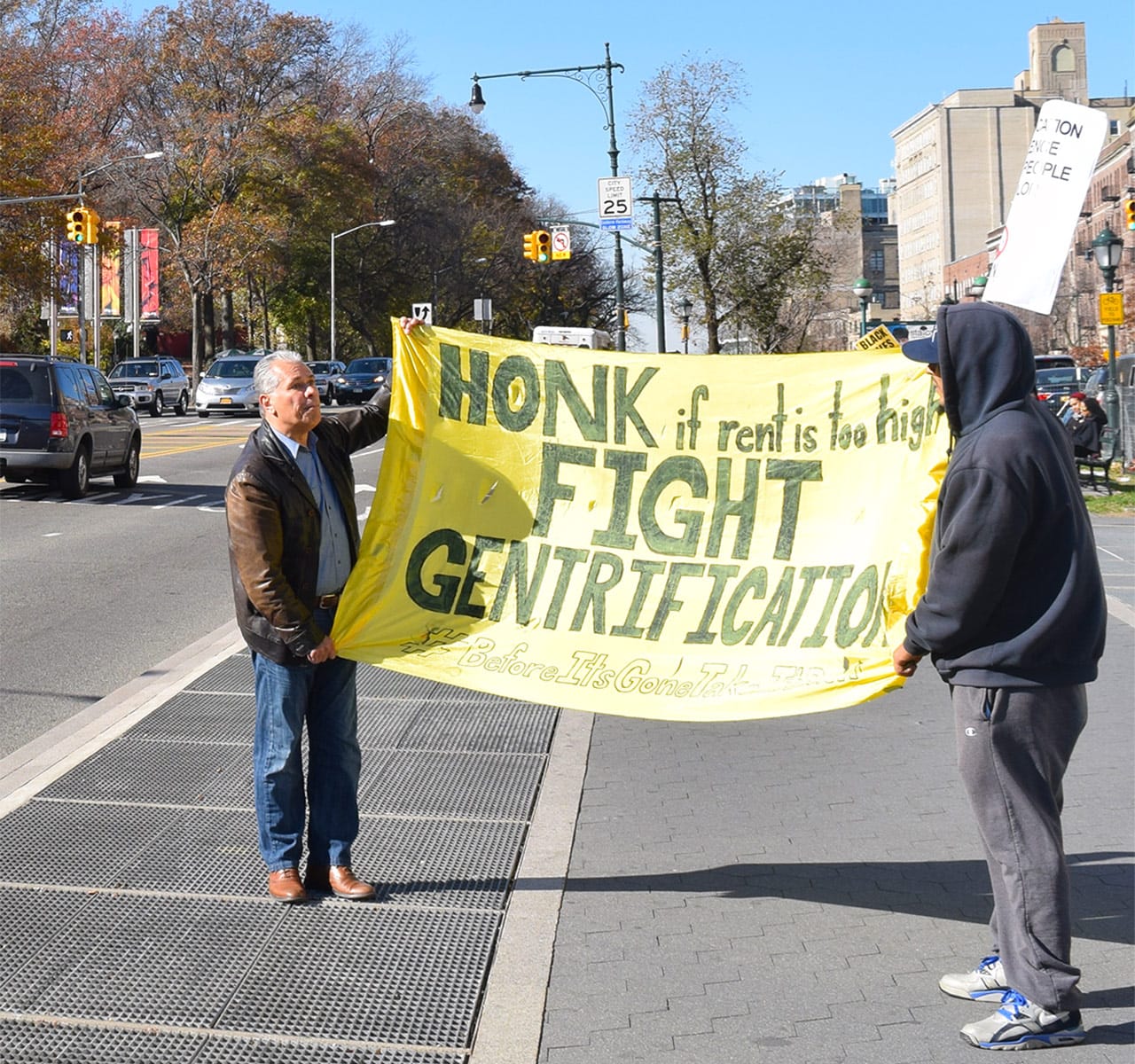 Anti-gentrification protesters hold up a sign on Eastern Parkway during a recent protest at the Brooklyn Museum.