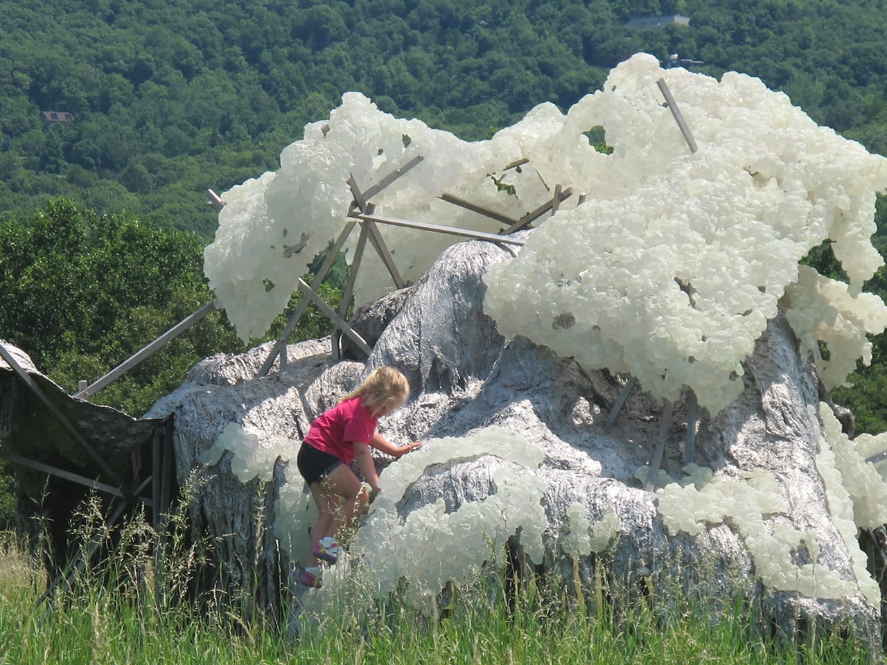 A child playing on Lynda Benglis's "Hills and Clouds (2014), cast phosphorescent polyurethane and stainless steel, 10'2" x 18'1" x 18'3" (courtesy the artist and Cheim & Read, New York)