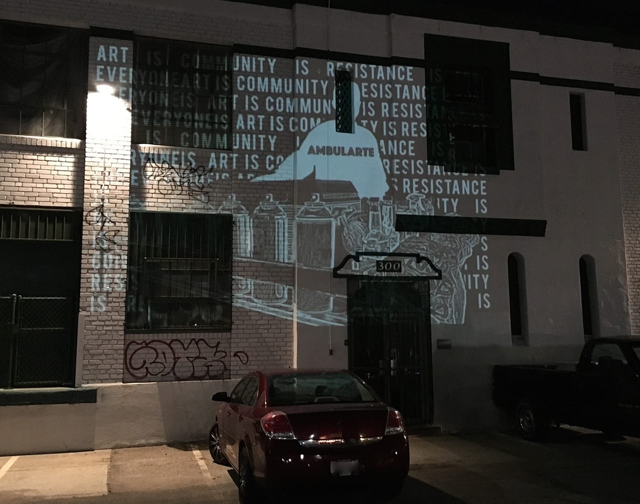 An event poster for the 'Ambularte' mobile art exhibit is projected on the front of Maccarone Gallery, Los Angeles