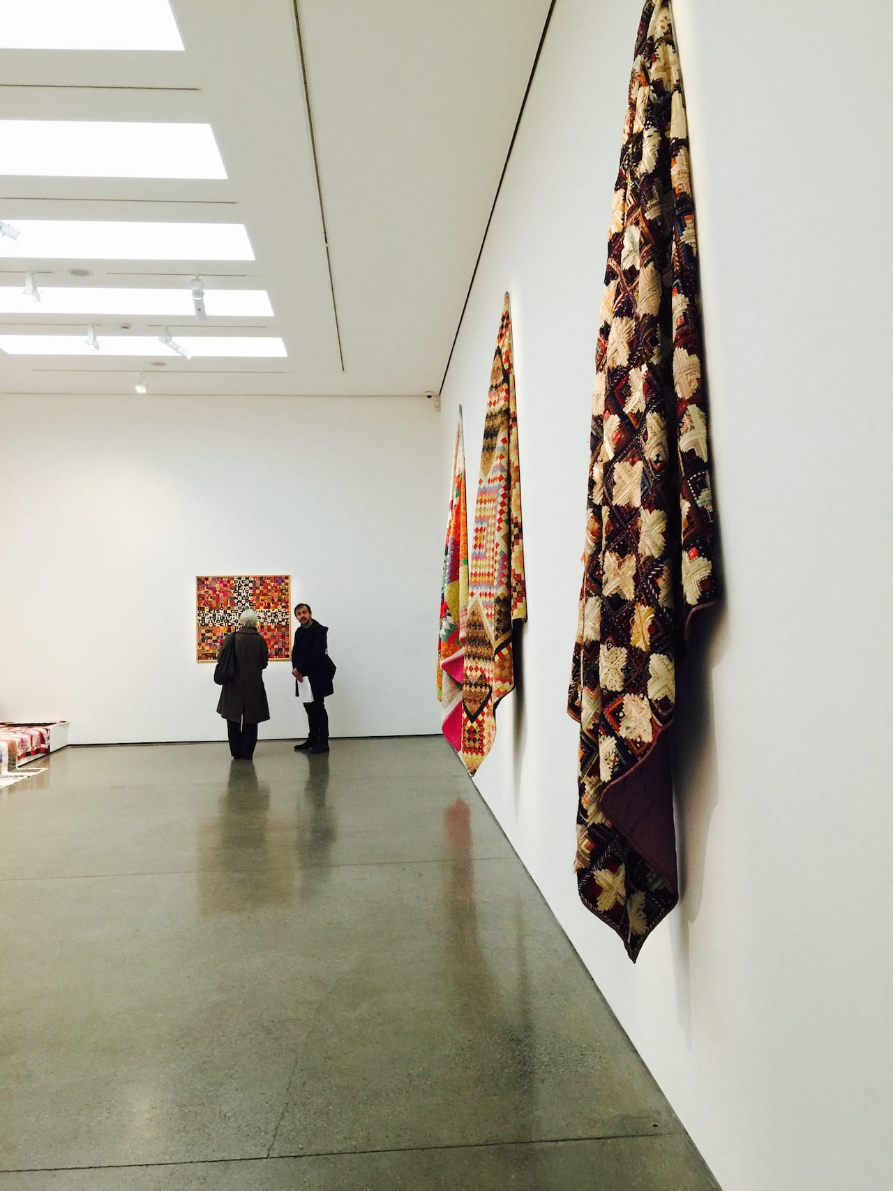 View of gallery with various quilts and Boetti