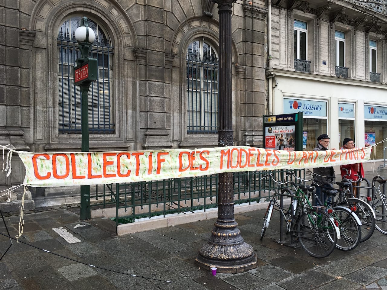 A banner hung by the Collectif des Modèles d’Art de Paris in the Place de l'Hôtel de Ville