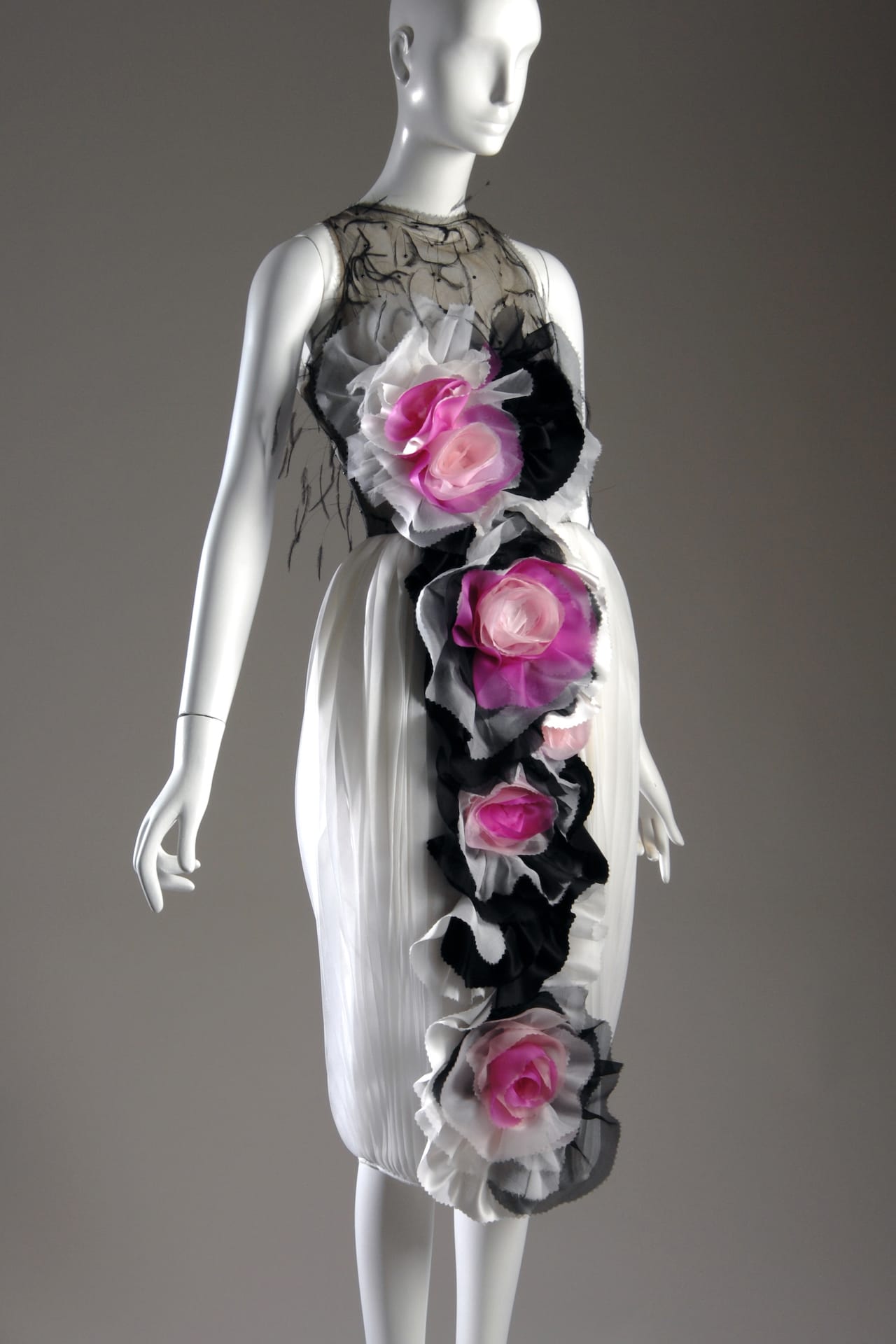 Long sleeveless evening dress in white sunburst pleated organza; ostrich silk tulle inverted, bodice lined in white feathers, faced with embroidered organza flowers