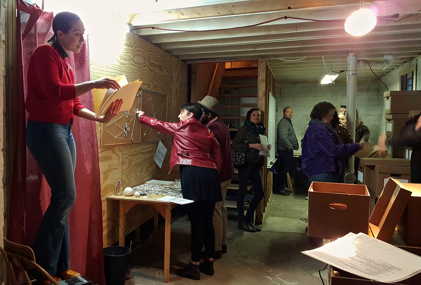 Bielby-as-Bielby reads out items from the archive to the audience in the basement (photo by the author for Hyperallergic)