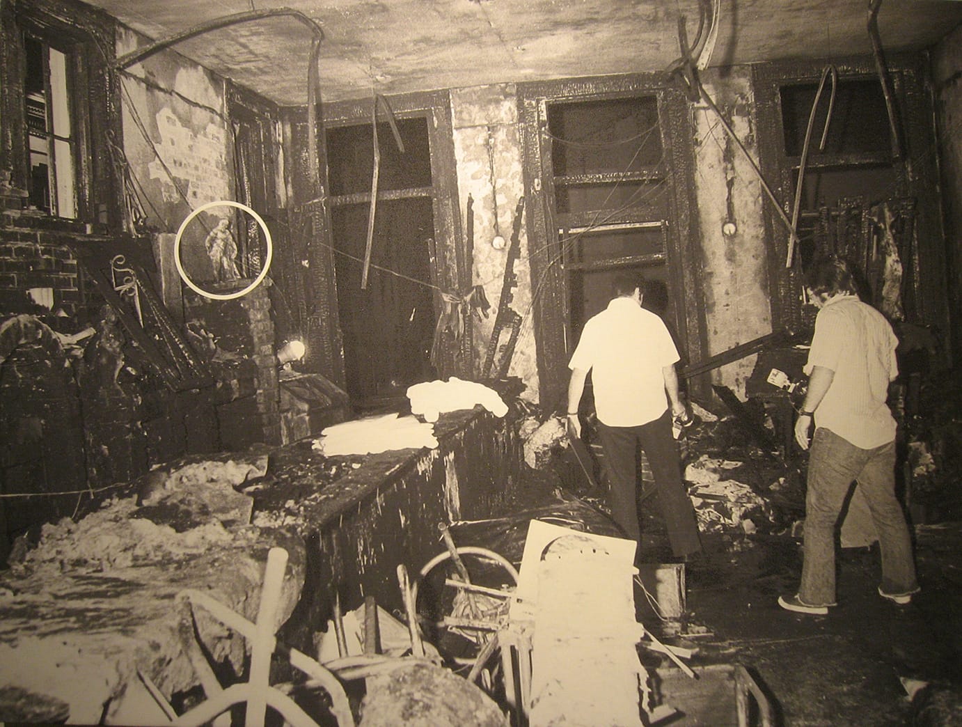 A photo of the fire wreckage of the Upstairs Lounge with a circle indicating the original position of the "Farnese Hercules" in the bar.