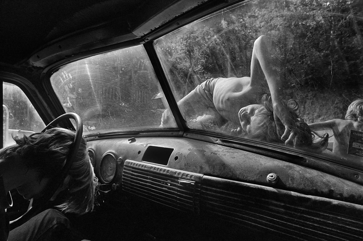 Caption: Boys sleep on the hood of a pickup truck on a hot summer day in Still House Hollow, Tennessee. Title: Still House Hollow, Tennessee, 1986