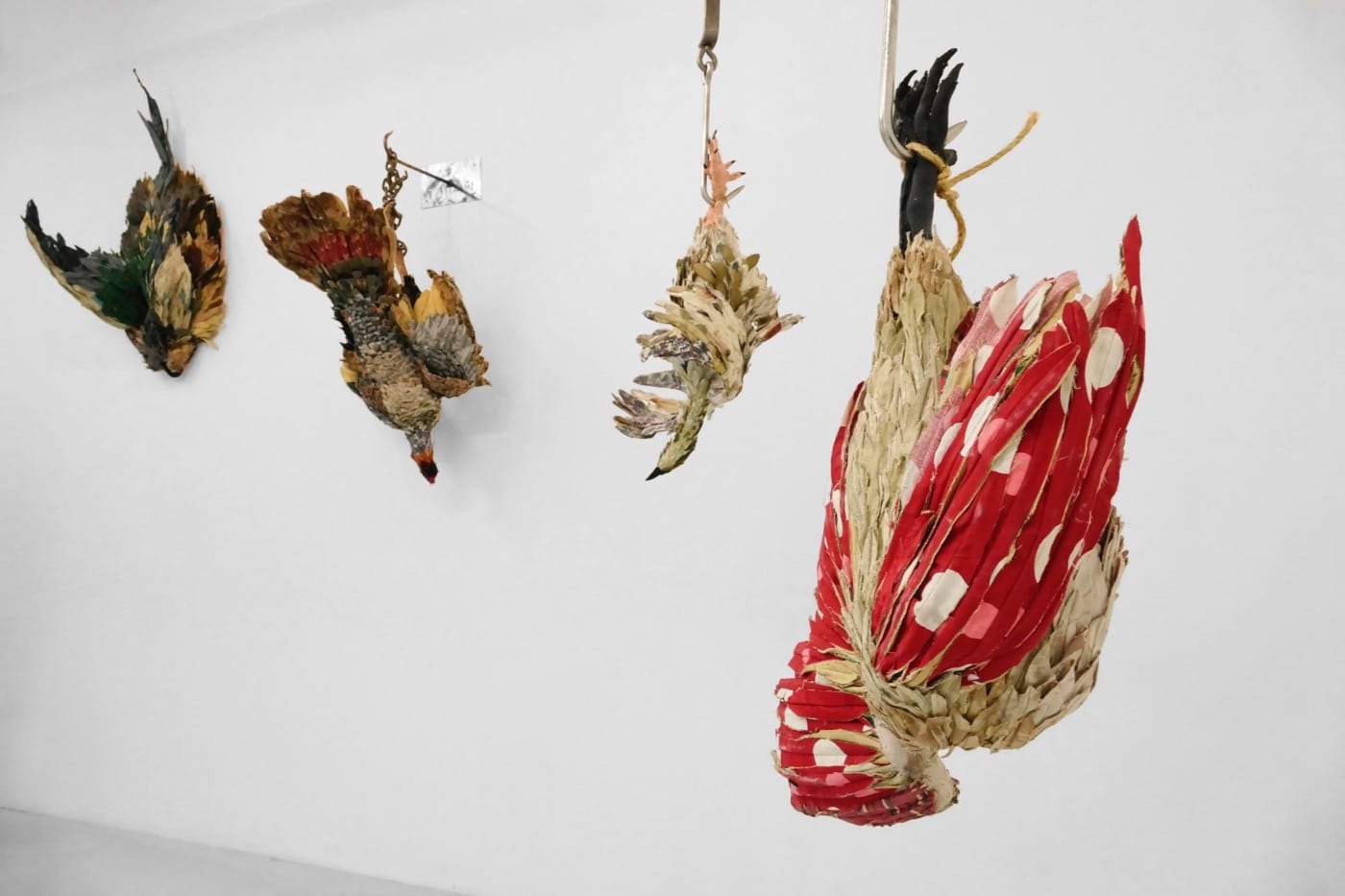 Installation view of <em>To Prevent Bad Luck </em> with four sculptures (2015-2016), discarded clothing, discarded upholstery fabric, meat hooks, variable dimensions