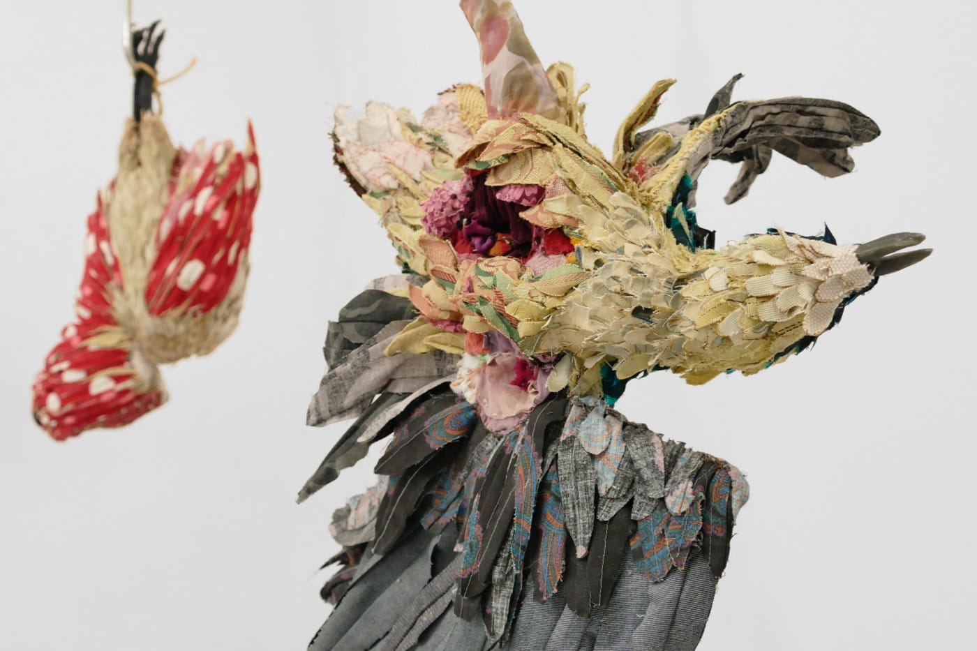 Installation view of <em>To Prevent Bad Luck</em> with two sculptures (2015-2016), discarded clothing, discarded upholstery fabric, meat hooks, variable dimensions