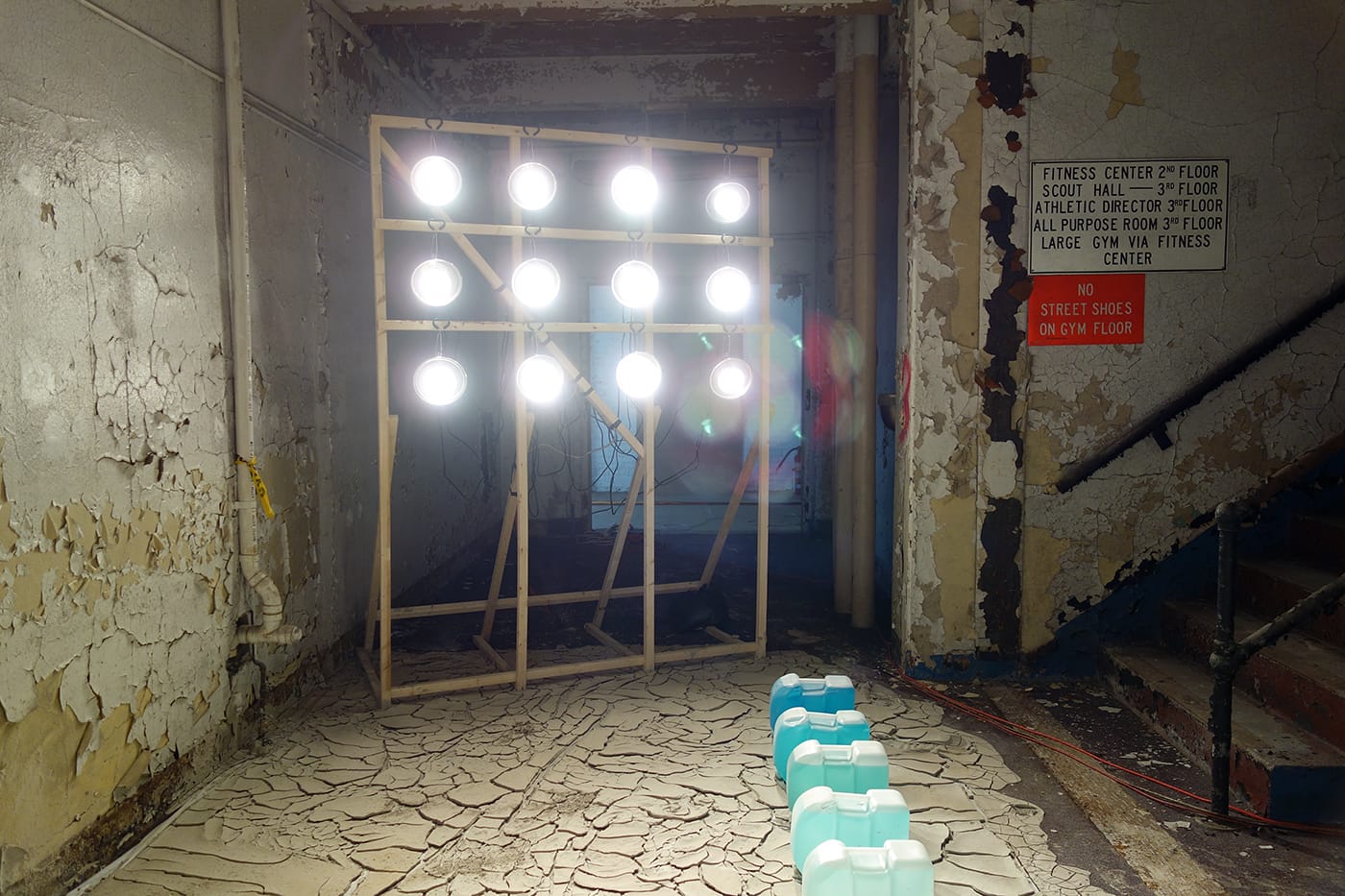 Trevor King, "The Well" (2017), 8 2.5 gallon water jugs blended with increasing percentages of Gatorade, approximately 1000lbs of clay slip, sand, wood, and 12 clip lamps with flood lights