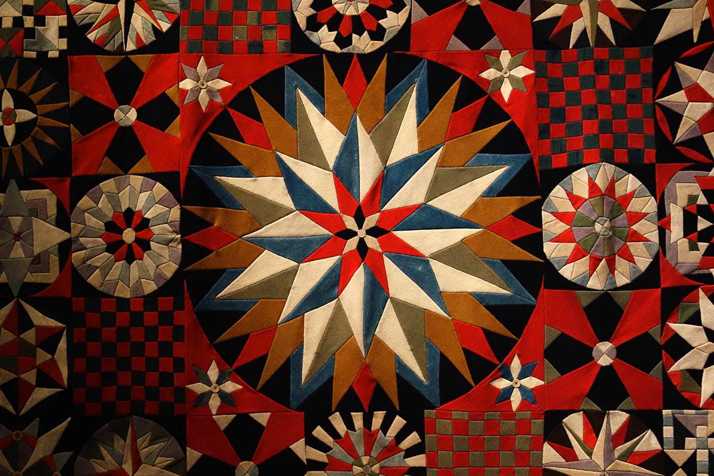 Detail of Soldier’s Quilt by an unidentified artist (Crimea, India, or United Kingdom, 1850–75), wool, probably from military uniforms; inlaid; hand-appliquéd with buttonhole fabric discs (photo by the author for Hyperallergic)