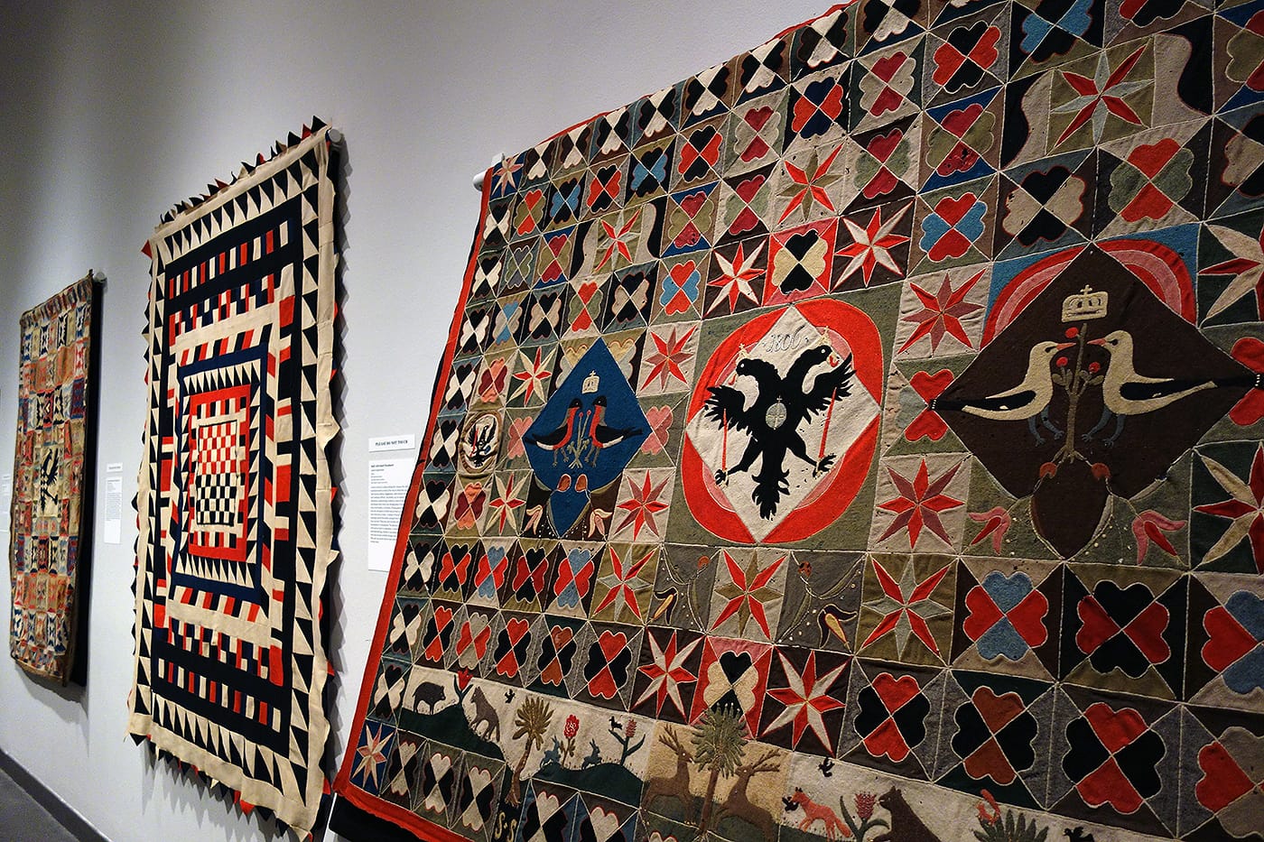 Installation view of <em>War and Pieced: The Annette Gero Collection of Quilts from Military Fabrics</em> at the American Folk Art Museum (photo by the author for Hyperallergic)