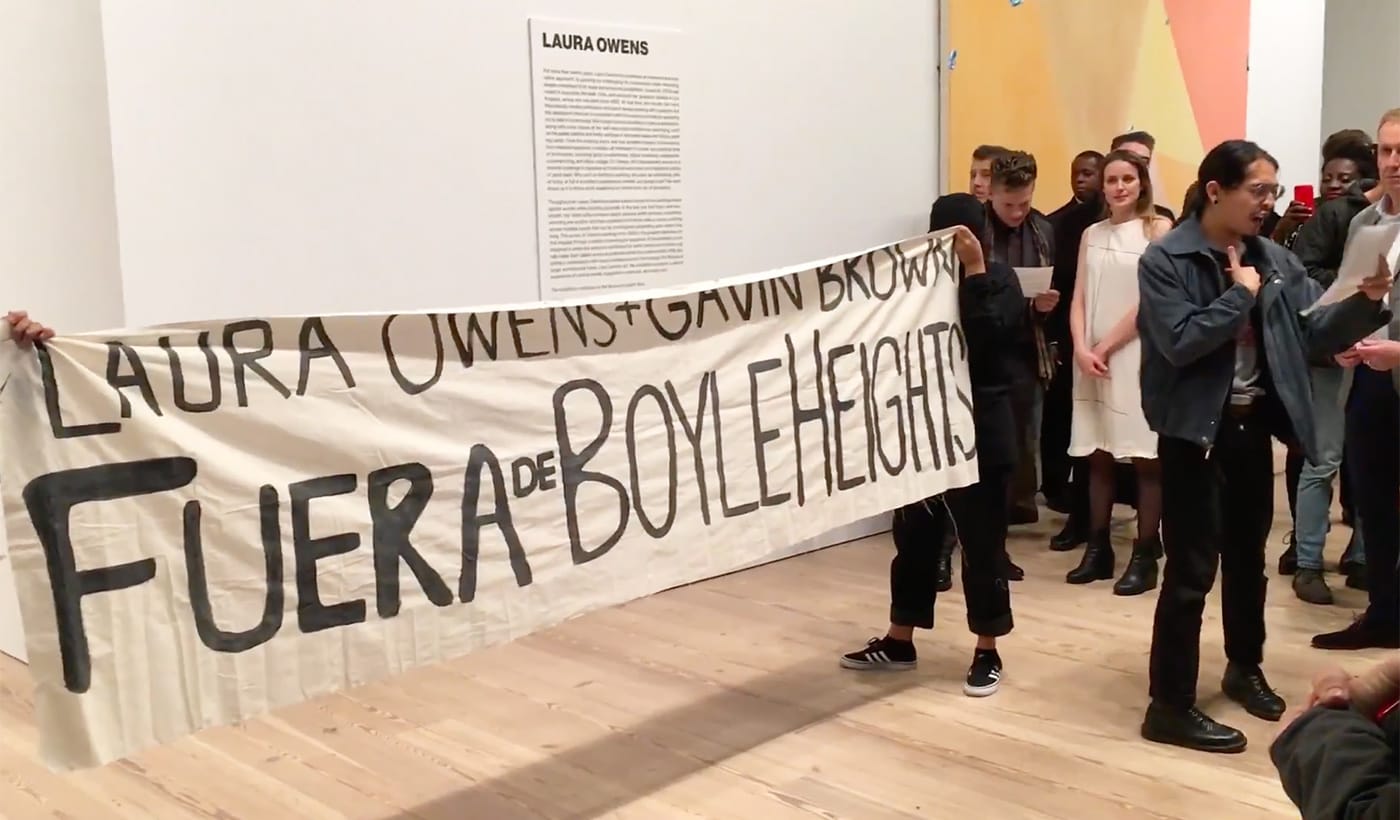 Members of Boyle Heights Alliance Against Artwashing and Displacement (BHAAAD) protest at the Whitney Museum during Laura Owens's opening on Wednesday, November 8. (screenshot by the author via YouTube)