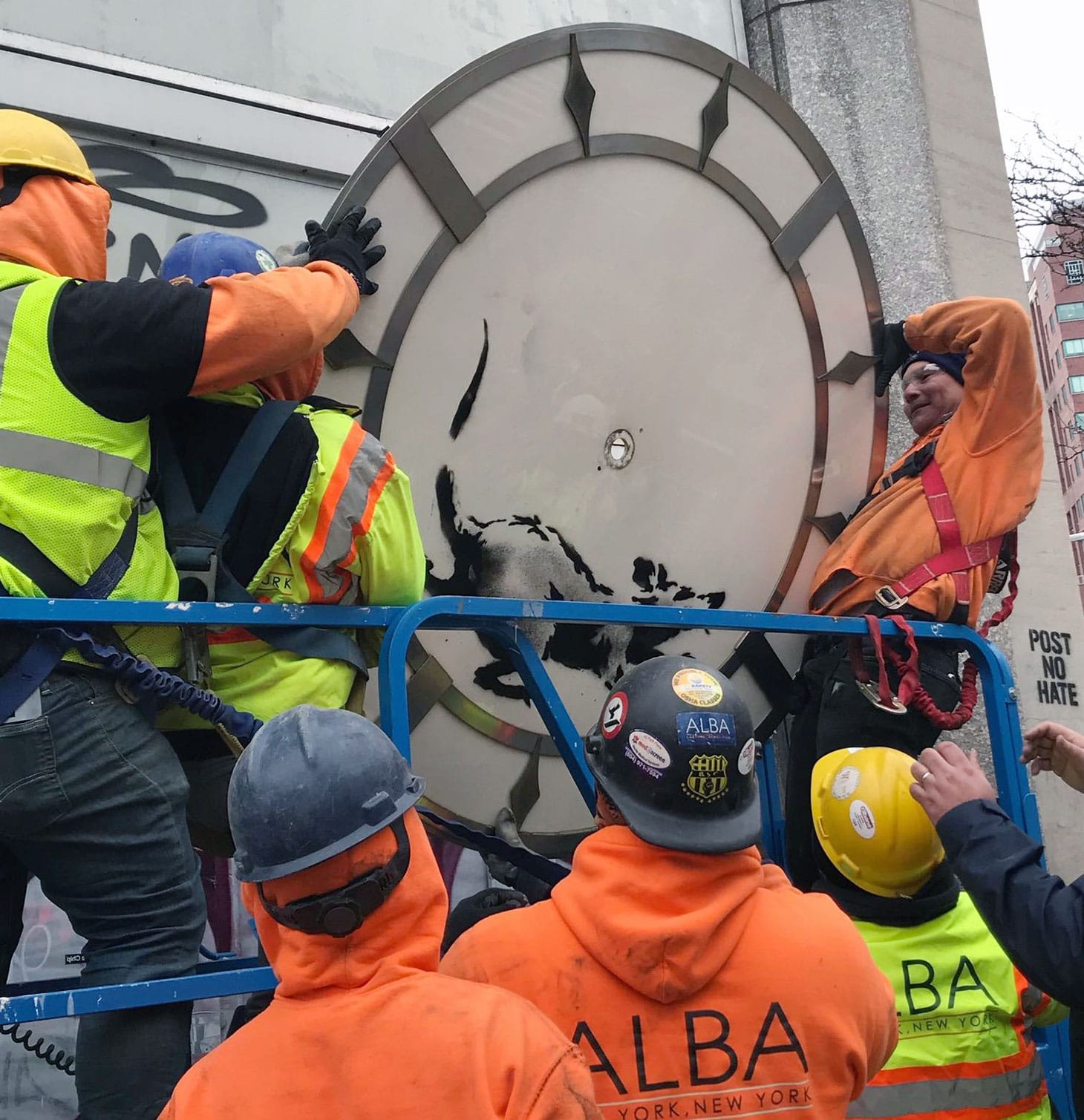 Workers taking down the Banksy at 14th Street and Sixth Avenue in Manhattan (photo by Melissa Stern for Hyperallergic)