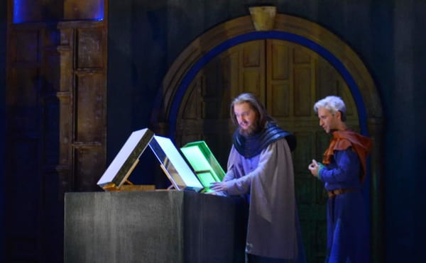 The Boy (countertenor Anthony Roth Costanzo) shows the completed pages of the book to the Protector (baritone Mark Stone), in